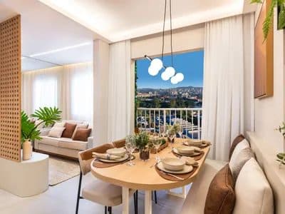 Sala de jantar integrada com mesa de madeira, cadeiras estofadas e lustre moderno, com vista para a varanda.