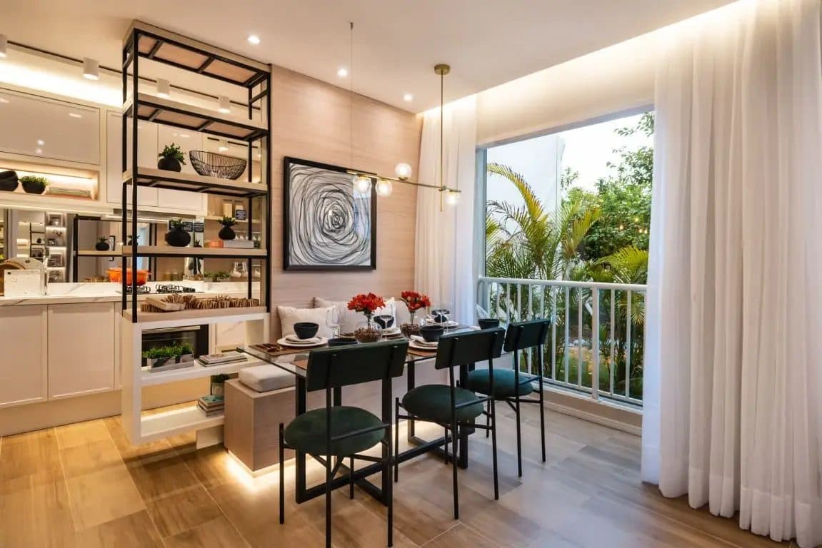 Sala de jantar com mesa de vidro, cadeiras verdes e estante decorativa vazada.