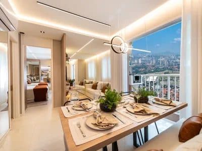 Sala de jantar integrada com mesa posta, iluminação moderna e vista para a cidade.