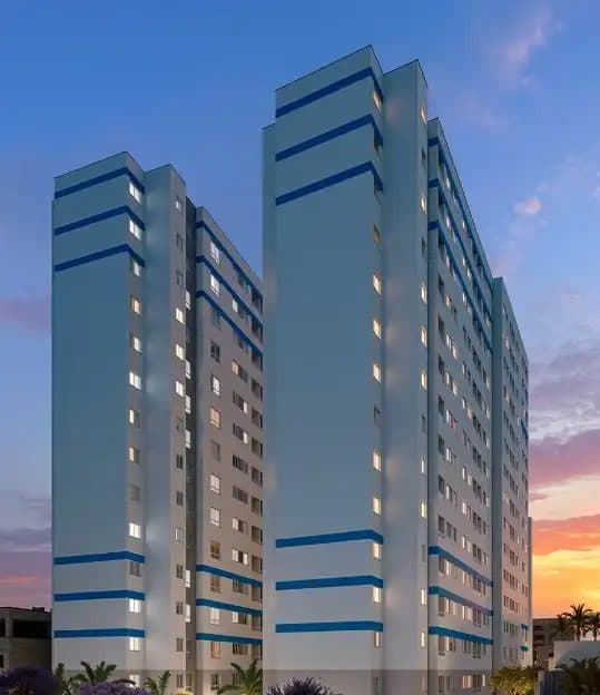 Vista externa de torres de apartamentos com pintura em tons de cinza e faixas azuis ao entardecer.